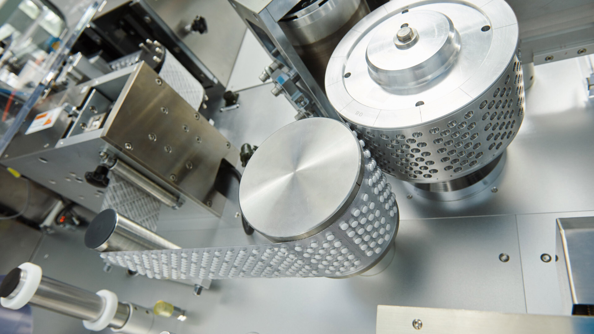 Detailansicht eines automatisierten Tablettenherstellungsprozesses in einem pharmazeutischen Produktionslabor. Die hochwertige Edelstahlmechanik und die präzisen Walzsysteme gewährleisten kontrollierte, GMP-konforme Fertigung und höchste Qualitätssicherung. Optimale Umgebung für pharmazeutische Analytik und zuverlässige Produktfreigabe. Detailansicht eines automatisierten Tablettenherstellungsprozesses in einem pharmazeutischen Produktionslabor. Die hochwertige Edelstahlmechanik und die präzisen Walzsysteme gewährleisten kontrollierte, GMP-konforme Fertigung und höchste Qualitätssicherung. Optimale Umgebung für pharmazeutische Analytik und zuverlässige Produktfreigabe.